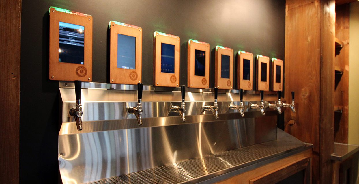 Photo of a row of 8 beverage taps with digital screens above the taps.